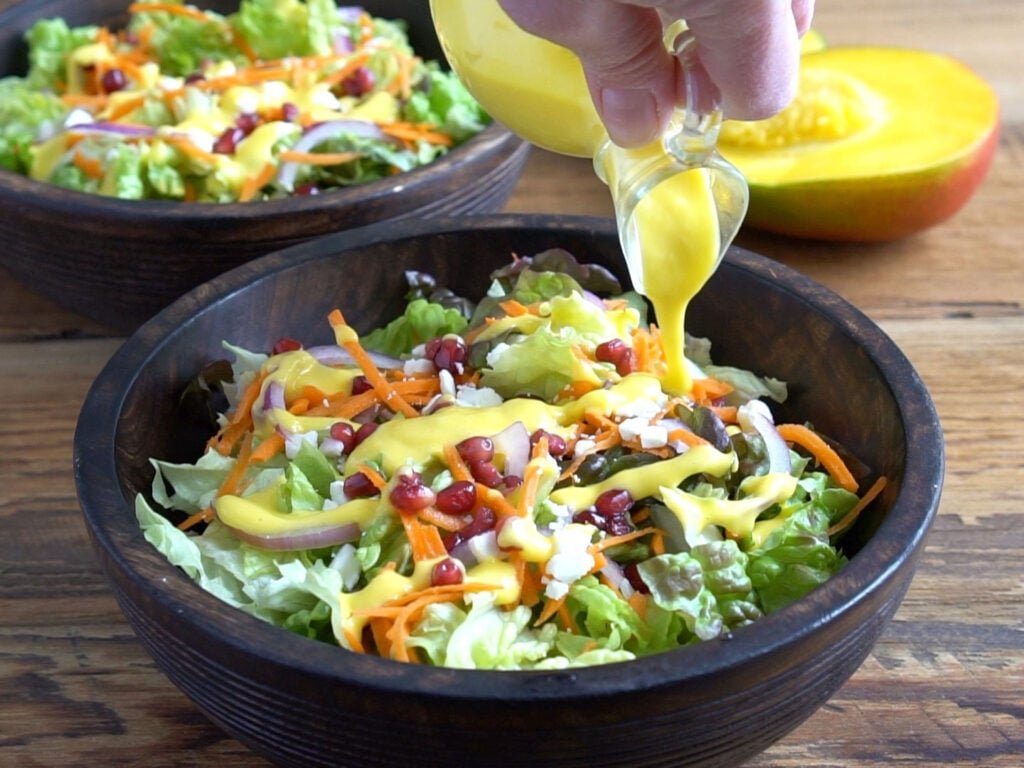 Mango salad dressing being poured onto a salad